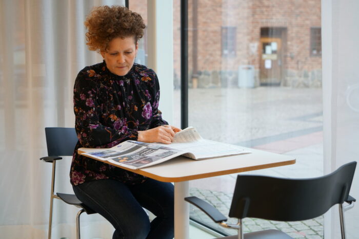 En person läser tidningen inne i Stadsbibliotekets tidningsrum